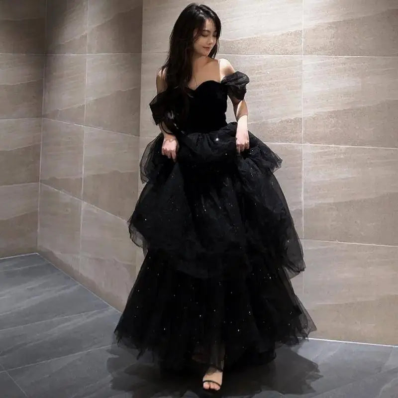 Elegant black velvet off-the-shoulder ball gown with layered tulle and sparkling embellishments for light luxury evening wear