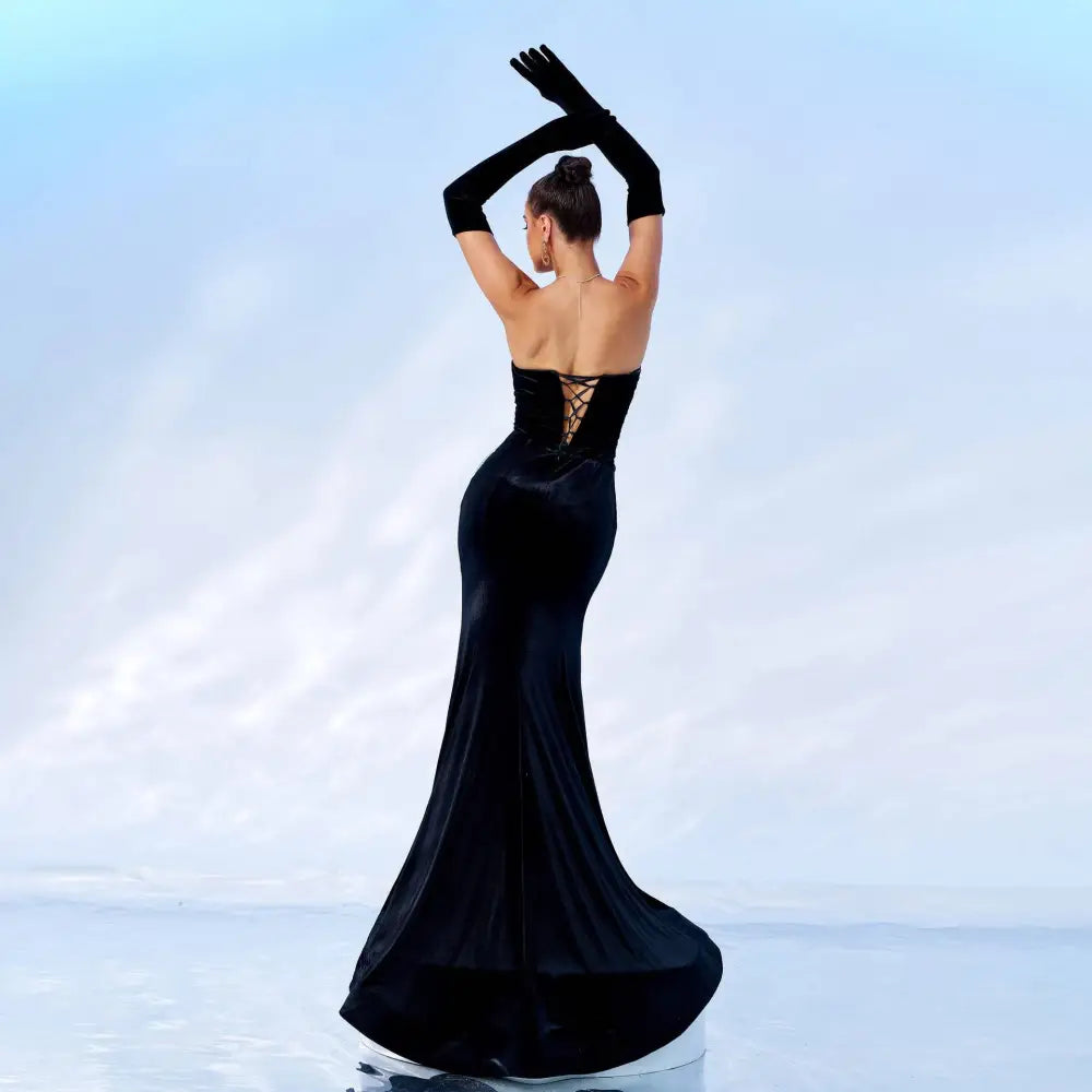 A sleek black velvet strapless mermaid gown with a corseted back and chest wrap hip design with long gloves