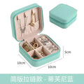 A compact mint green leather jewelry box with zipper compartments for organizing accessories in a black wall mounted portable women makeup bag