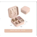 A blush pink compact jewelry box with zipper closure and compartments for a black wall mounted portable women makeup bag