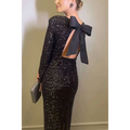 A shimmering black winter sexy backless sequined mermaid gown with long sleeves and a dramatic back bow shown from the back