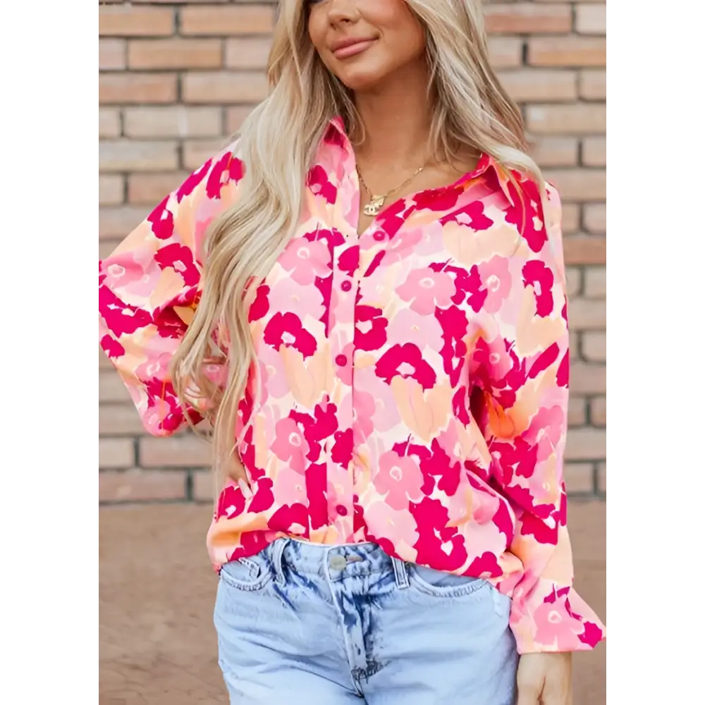 A woman wearing a vibrant pink blooming floral print shirt with long print puff sleeves and coral accents