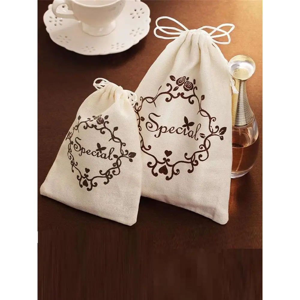 Cream-colored drawstring gift bags with black floral embroidery and special script for blue butterfly mori style shark clip