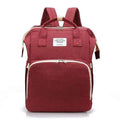 A maroon fabric backpack with beige trim and white living traveling share label, suitable as a denim large capacity mommy bag