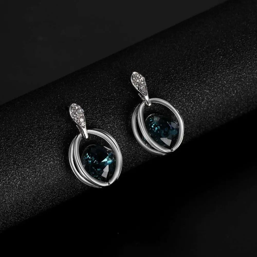 Silver necklace with deep blue gemstone and diamond accents as part of a crystal bridal necklace and earrings set featuring elegant oval design