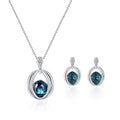 Silver crystal bridal necklace and earrings set featuring a deep blue gemstone in an oval wireframe with diamond accents