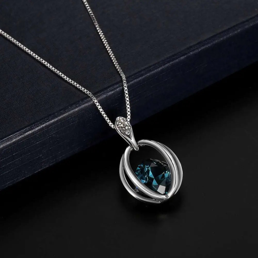Silver crystal bridal necklace and earrings set featuring a teardrop blue gemstone with intertwined metal loops and accents