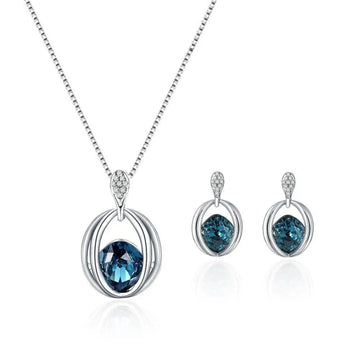 Silver necklace with deep blue gemstone and diamond accents as part of a crystal bridal necklace and earrings set featuring elegant oval design