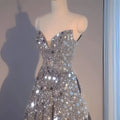 A shimmering silver heavy industry wedding evening dress with a sweetheart neckline and mirror-like embellishments