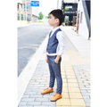 A young boy wearing a blue plaid children’s three-piece fashion suit with a navy comfort vest and trousers