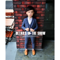 A child wearing a blue plaid children’s three-piece fashion suit with matching vest and tan leather shoes for comfort use