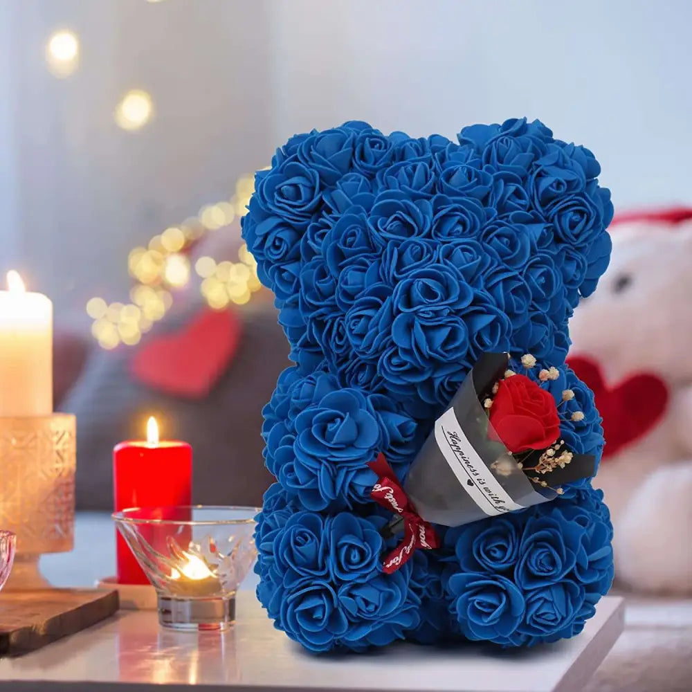 A plush blue rose bear made of preserved rose flower holding a bouquet of red and white flowers in gift box