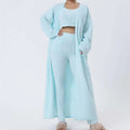 A cozy pajama set in blue shimmer knit featuring a cropped top with square neckline, wide-leg pants, and an open cardigan
