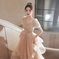 A blush beaded tulle luxury evening dress with a beaded bodice, puff sleeves, and layered tulle skirt