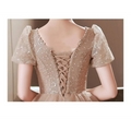 Luxury evening dress in shimmering champagne-colored blush with sequins, puffy sleeves, and lace-up back shown from behind