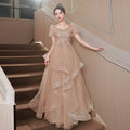 A shimmering champagne-colored blush beaded tulle luxury evening dress with intricate bodice beading and layered skirt