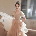 Blush beaded tulle luxury evening dress with a blush pink lace gown, puffy short sleeves, and a shimmering champagne-colored blush bodice