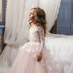 A young girl wearing a blush lace princess dress with intricate white lace sleeves and butterfly appliqués for flower girl evening