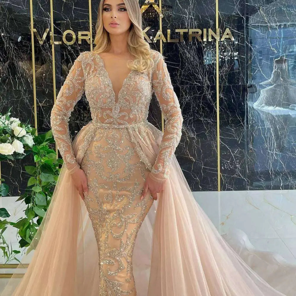 Blush pink beaded mermaid-style simple wedding dress with intricate gold beading, sheer sleeves, and tulle train