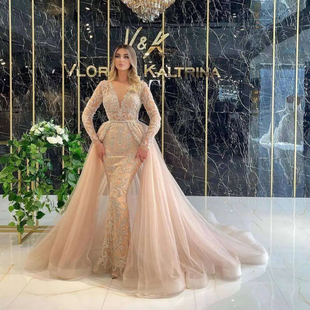 Blush pink beaded mermaid wedding dress with long sleeves and gold beading featuring a voluminous tulle train