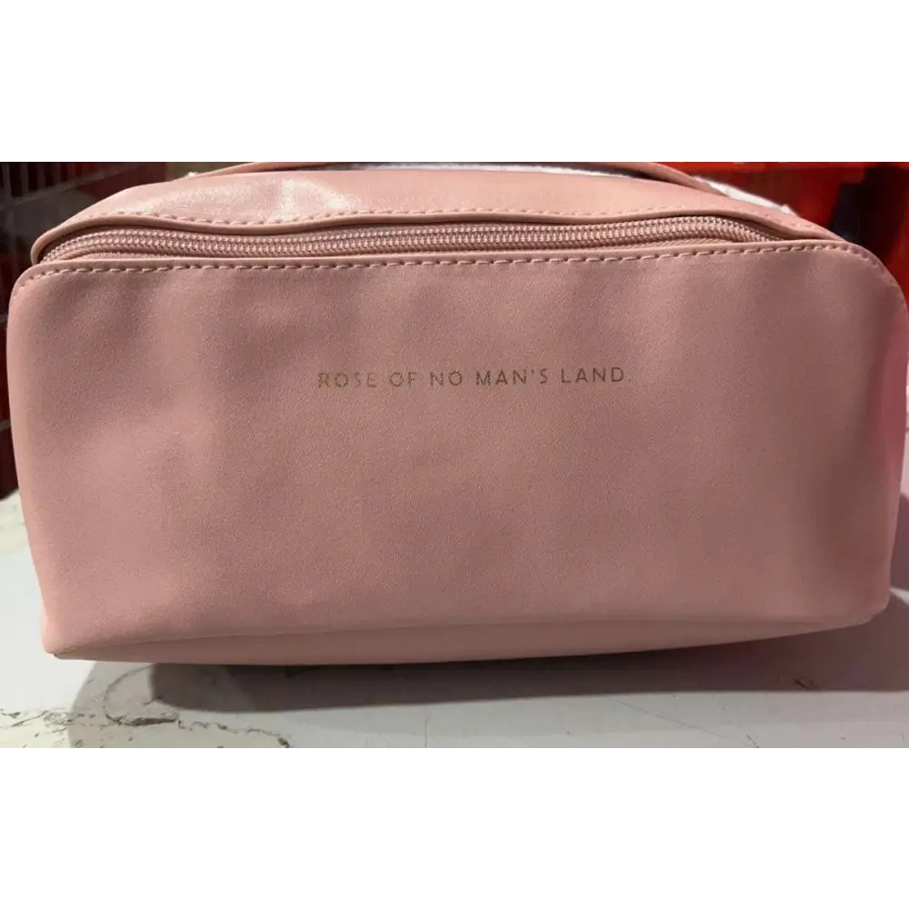 A blush pink large travel cosmetic bag made of soft leather with an embossed rose of no mans land logo