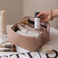 Blush pink large travel cosmetic bag with beige exterior, gold zipper, and subtle embossed text makeup bag