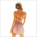 A soft blush pink romper image featuring thin straps and a tied back design for luxury women’s fashion