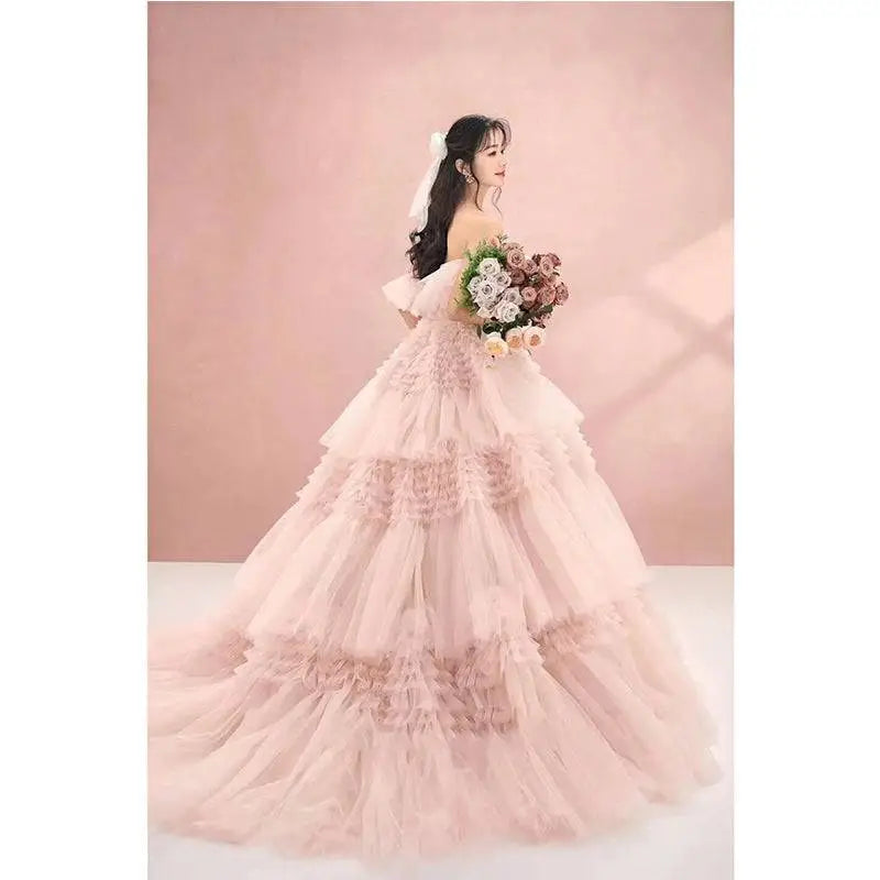 A blush pink tiered photography pettiskirt colored mesh dress with ruffled layers and off-the-shoulder sweetheart neckline