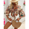 Beige woven straw handbag with curved handle and natural fiber texture paired with bohemian style printed top