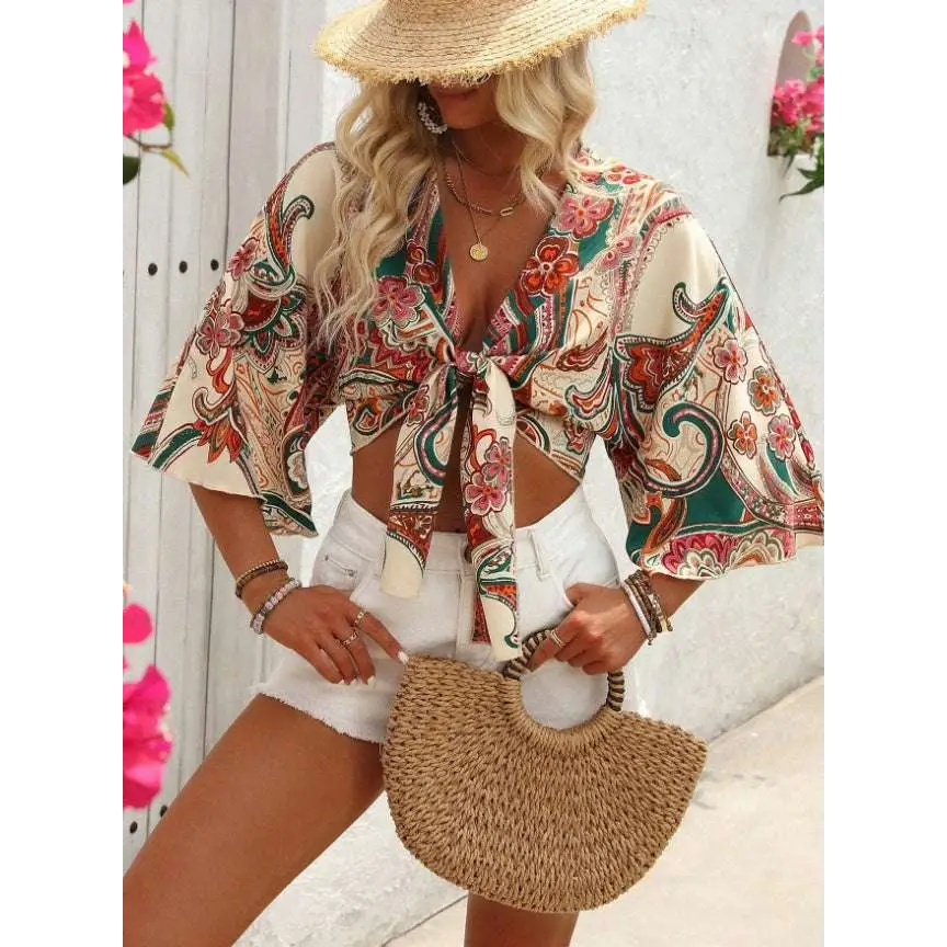 Beige woven straw handbag with curved handle and natural fiber texture paired with bohemian style printed top