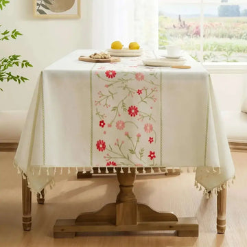 Cream-colored boho floral linen tablecloth with embroidered red and pink flowers and tassels farmhouse table cover