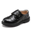 Boys black patent leather school shoe with brogue detail and velcro strap in british casual single style