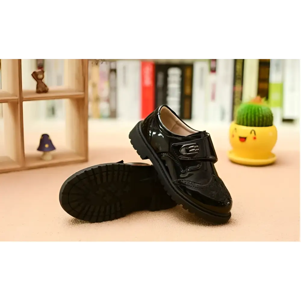 Boys black patent leather dress shoe with brogue detail and velcro strap in british casual single style