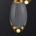 A sleek translucent gray glass raindrop pendant light with polished brass accents and warm-toned bulbs for contemporary elegance