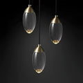 Three elegant brass and glass raindrop pendant lights with clear egg-shaped shades for contemporary elegance