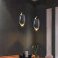 Two elegant brass and glass raindrop pendant lights with translucent shades and gold-toned accents showcasing contemporary elegance