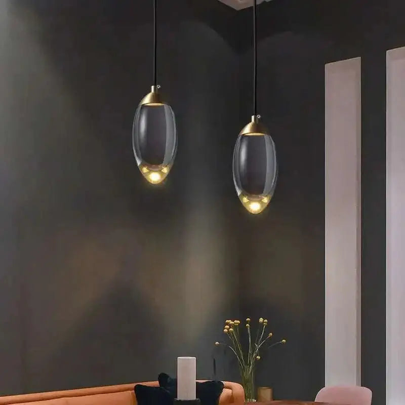 Two elegant brass and glass raindrop pendant lights with translucent shades and gold-toned accents showcasing contemporary elegance