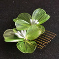 A delicate green wirework four-leaf clover bridal headdress with fairy golden flower centers and gold-toned teeth comb