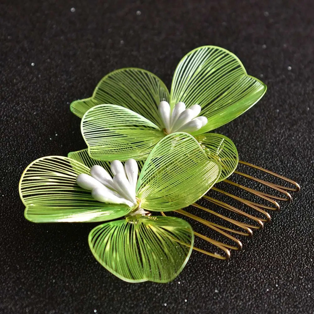 A delicate green wirework four-leaf clover bridal headdress with fairy golden flower centers and gold-toned teeth comb