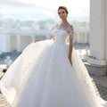 White bridal mesh long sleeve wedding dress with lace bodice and voluminous skirt for elegant bridal wear