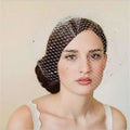 A delicate white bridal veil rhinestone hole mesh headdress draped elegantly over styled hair