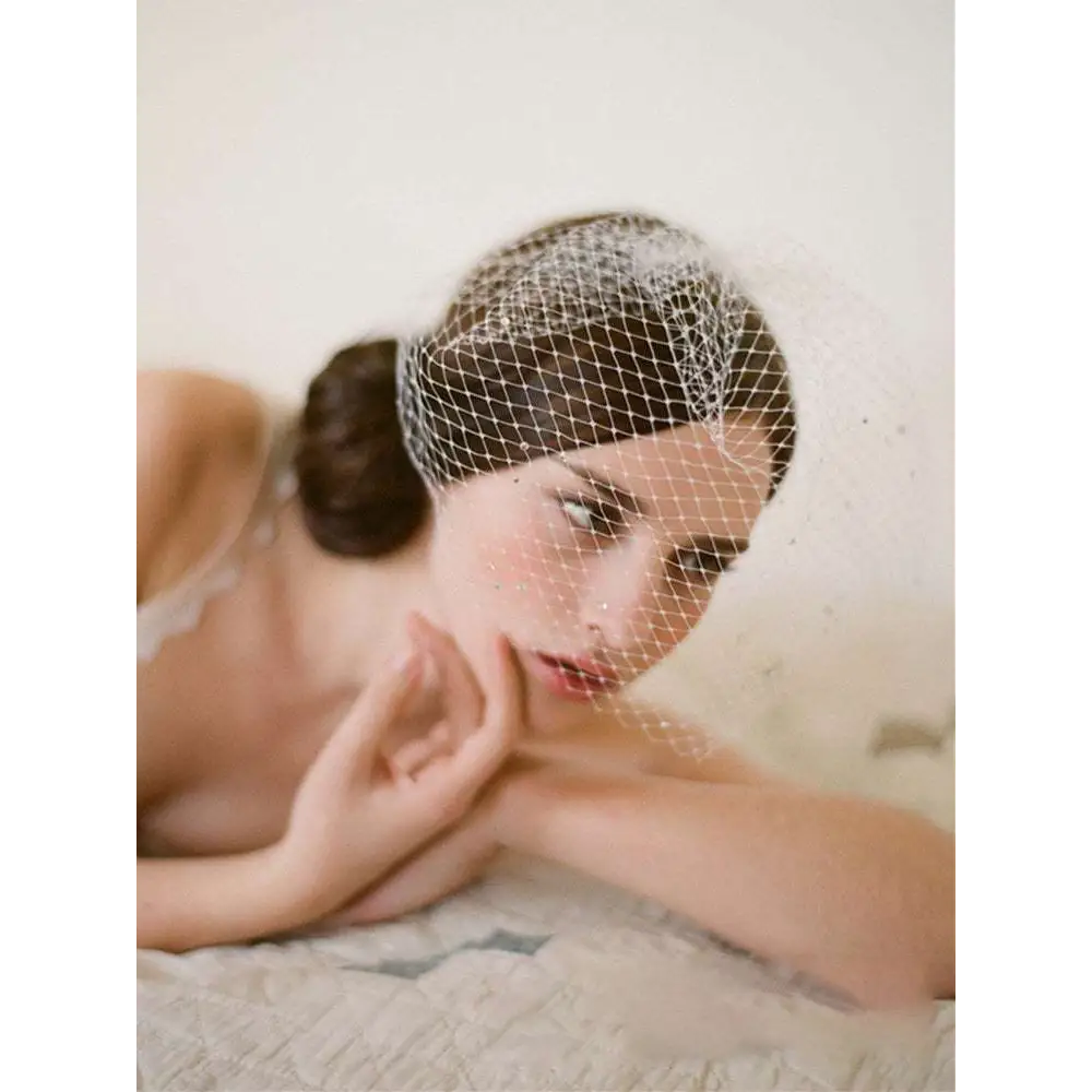 Delicate white bridal veil rhinestone large hole mesh headdress gently draping over the model’s head