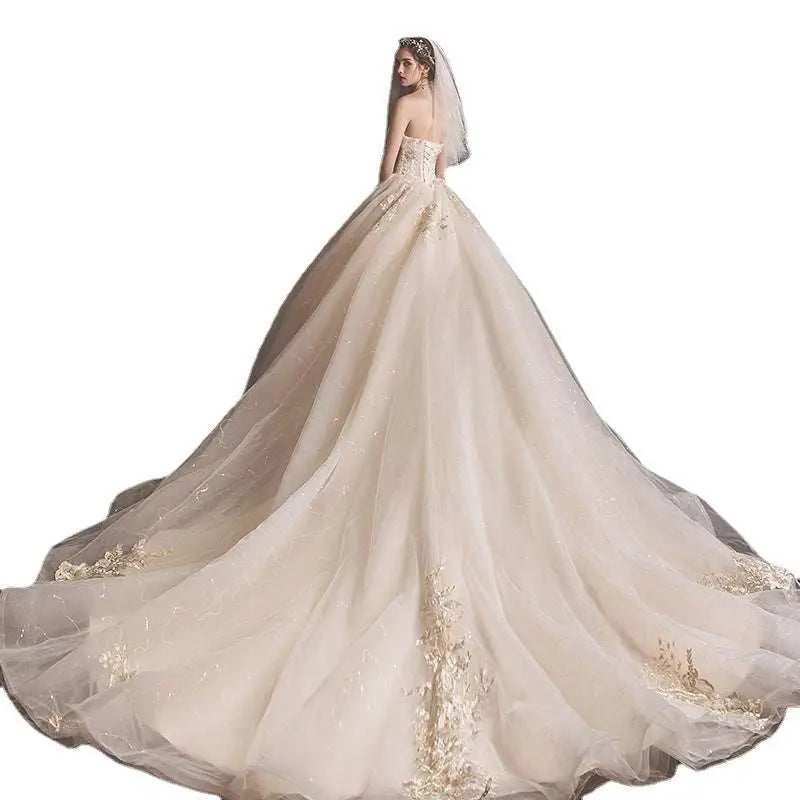 A strapless ivory bride summer tube gown with fitted bodice and mori style trailing skirt featuring gold floral embroidery