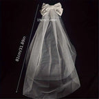 A delicate white tulle bridal veil with a white satin bow and bride to be embroidery for minimalism fashion wedding decoration