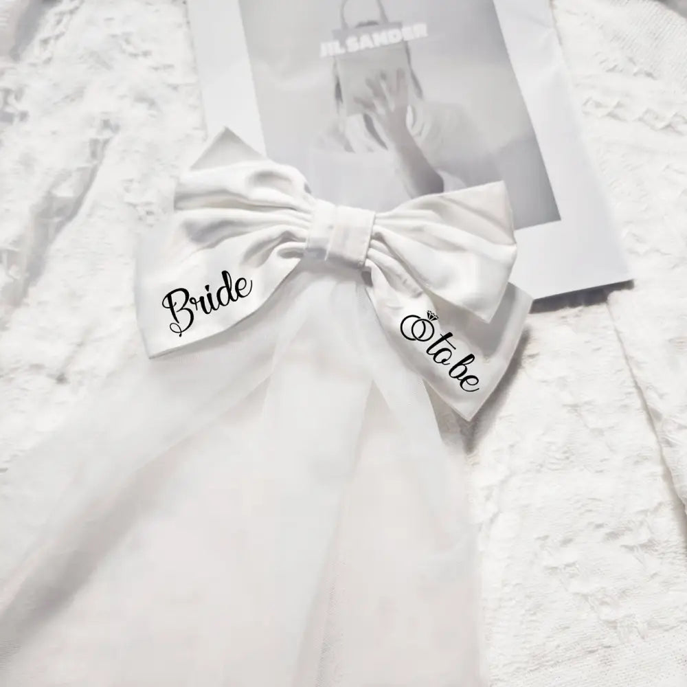 White satin bow embroidered with bride to be in black script featuring diamond detail for minimalism fashion wedding decoration
