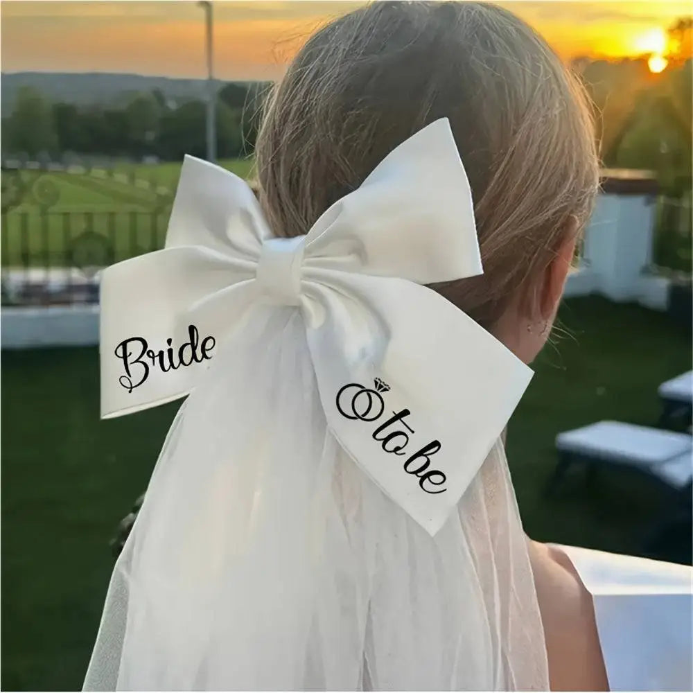 White satin bow with bride to be printed in black cursive and a diamond ring icon for minimalism fashion wedding decoration