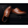Pair of brown leather oxford dress business shoes with brogue detailing and lace-up closure