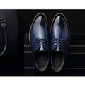 A pair of polished navy blue leather oxford dress business shoes with white stitching and laces