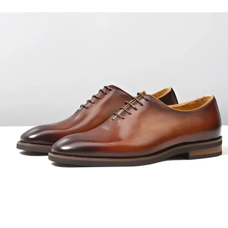 A pair of polished brown leather oxford wedding shoes for men with a classic pointed toe and dark laces