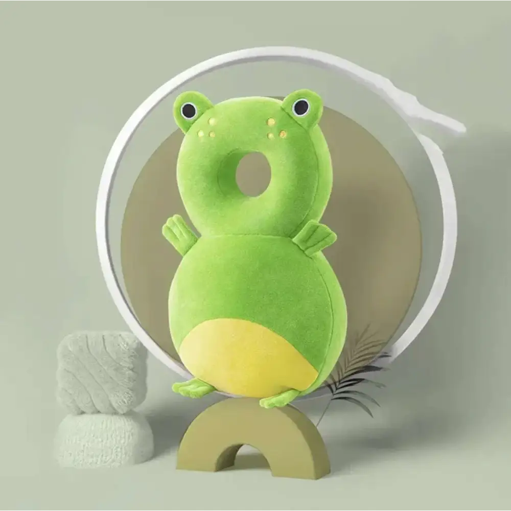 A plush green frog-shaped toddler head protection pad with bunny ear mesh designed for comfort and safety